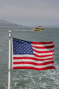 American flag in sea against sky