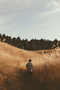 Man riding bicycle on field against sky