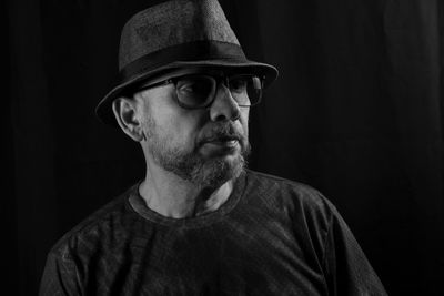 Black and white portrait of a man wearing a hat and glasses. isolated on black background.