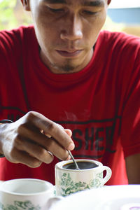 Midsection of man with coffee cup sitting outdoors