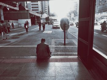 Rear view of people walking on street amidst buildings in city