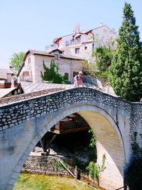 Arch bridge over old building in city against sky