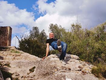 Low angle view of man sitting on rock