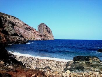 Scenic view of sea and mountains against clear blue sky