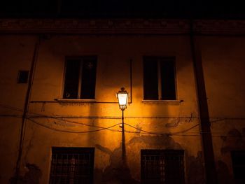 Low angle view of illuminated street light against building at night