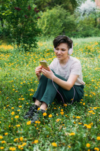 Young woman in headphones and with smartphone using audio chat social networking app