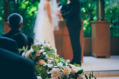 Close-up of flowers with bride and groom in background