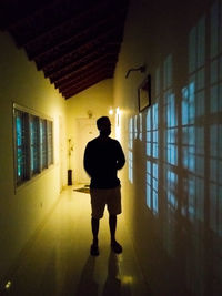 Rear view of man walking in illuminated building