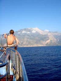 Rear view of man sailing on sea against sky