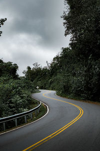 Empty road amidst trees against sky