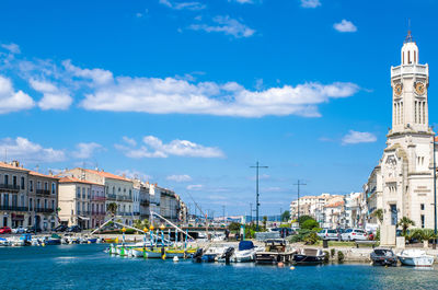 Harbor by city against cloudy sky