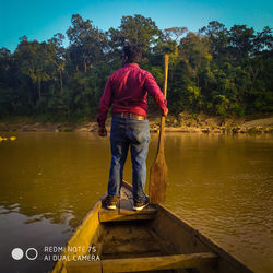 Rear view of man standing by lake against sky