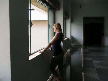 Side view of woman looking through window