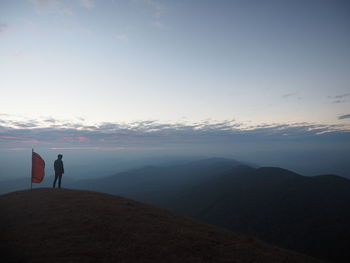 Rear view of silhouette man standing on mountain against sky