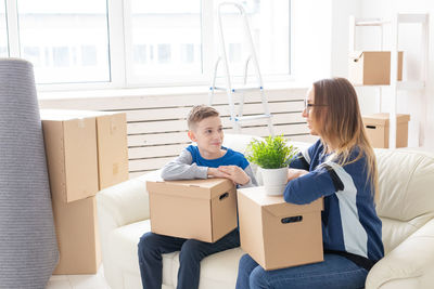 Happy friends sitting in box at home