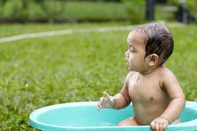 Close-up of shirtless baby boy in tub