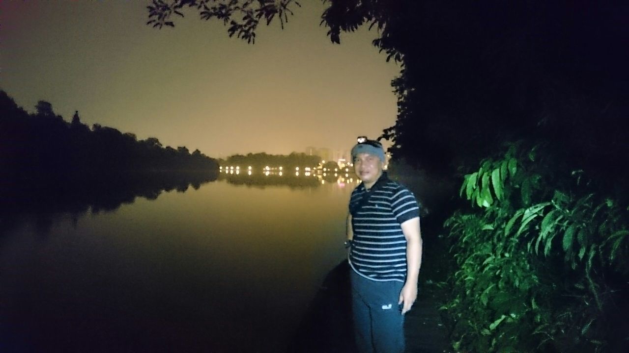 water, tree, reflection, lake, clear sky, tranquility, copy space, blue, nature, rear view, outdoors, leisure activity, tranquil scene, standing, beauty in nature, one animal, scenics, river