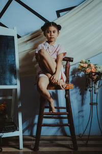 Portrait of young woman sitting against built structure