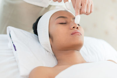 Young woman being massaged on face by therapist in spa