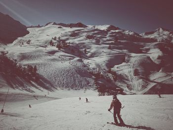 Man skiing on snowcapped mountain against sky