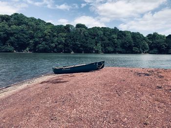 Boat moored on beach against sky