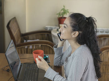 Side view of woman using mobile phone at home