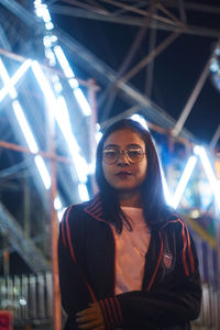 Portrait of smiling young woman standing in illuminated building