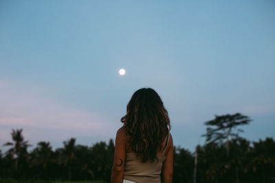 Rear view of man standing against moon