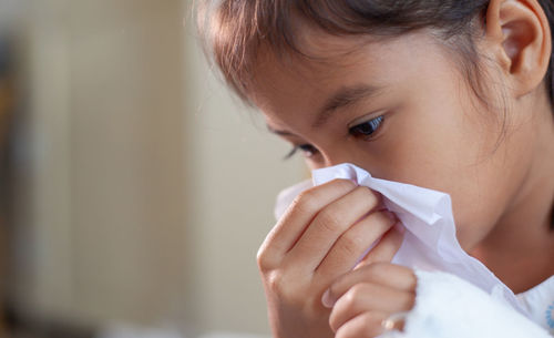 Close-up of cute girl blowing nose