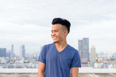 Portrait of smiling man standing against sky in city