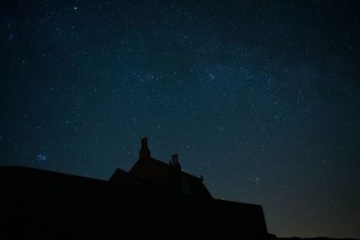 Low angle view of silhouette building against sky at night