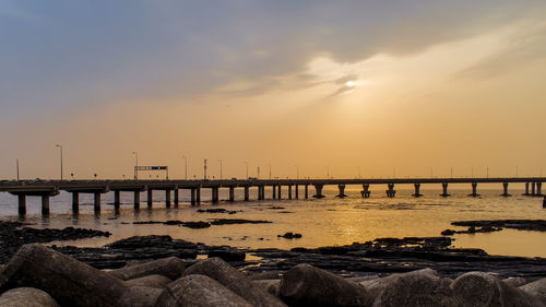 Pier over sea against sky during sunset