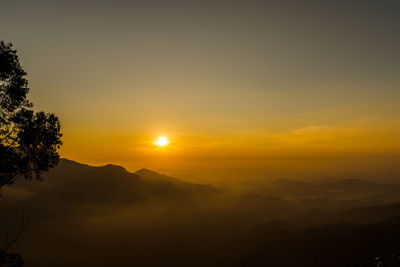 Scenic view of silhouette mountains against orange sky