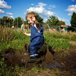 Full length of happy playful boy on muddy field