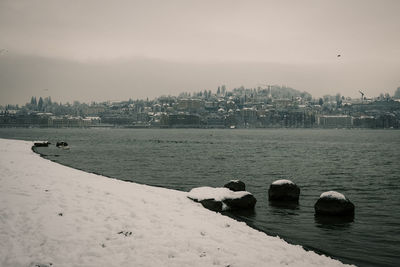 Scenic view of sea by cityscape against sky