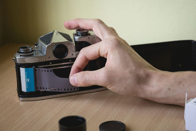 Cropped hand of person adjusting film negative in camera on table