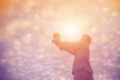 Low section of man standing against sky during sunset