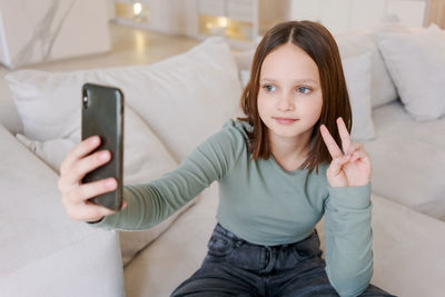 Young woman using mobile phone while sitting on sofa at home