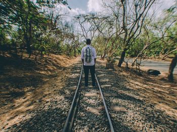 Rear view of man standing on railroad track