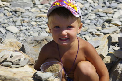 Portrait of cute boy with stones at beach