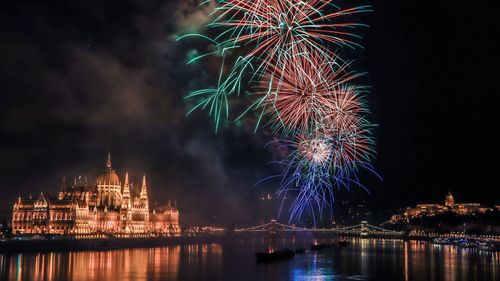 Firework display by parliament building over danube river at night