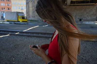 Side view of young woman using phone while standing on bus