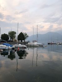 Boats moored in harbor at sunset