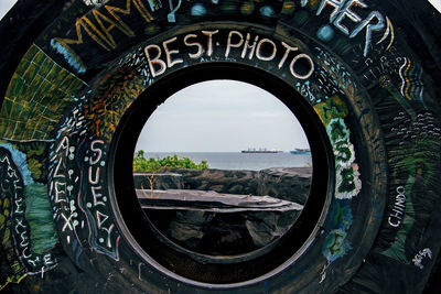 Close-up of water wheel against sky seen through arch