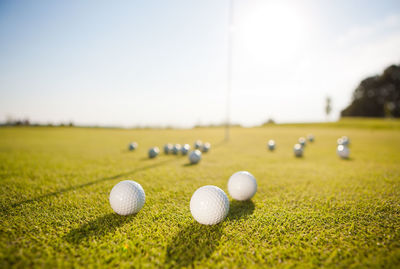 Close-up of golf balls on grass against sky