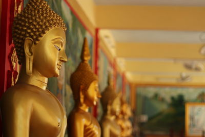 Some golden color buddha statues lined up against a blurred background