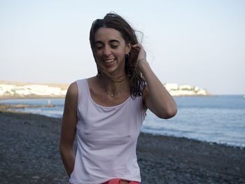 Young woman using phone while standing on beach