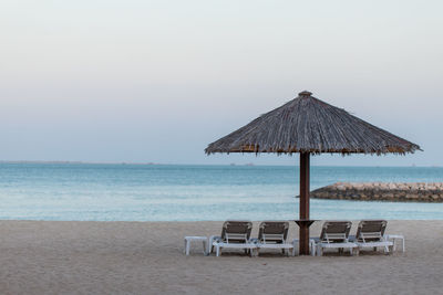 Chair on beach against clear sky