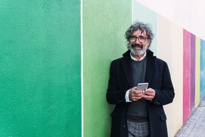 Portrait of young man standing against wall