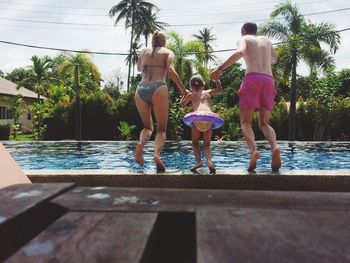 Full length of children standing by swimming pool against sky